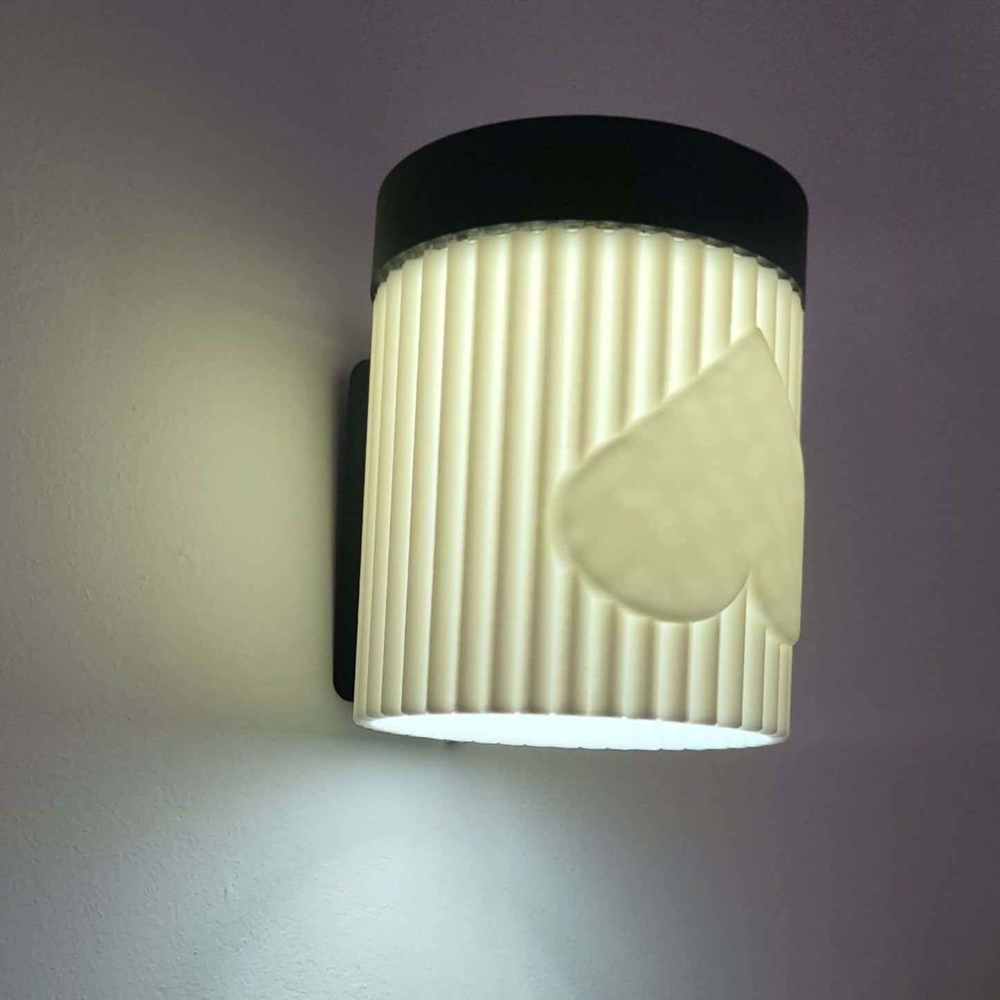 Wall-mounted light fixture with ribbed design and heart shape on a gray background