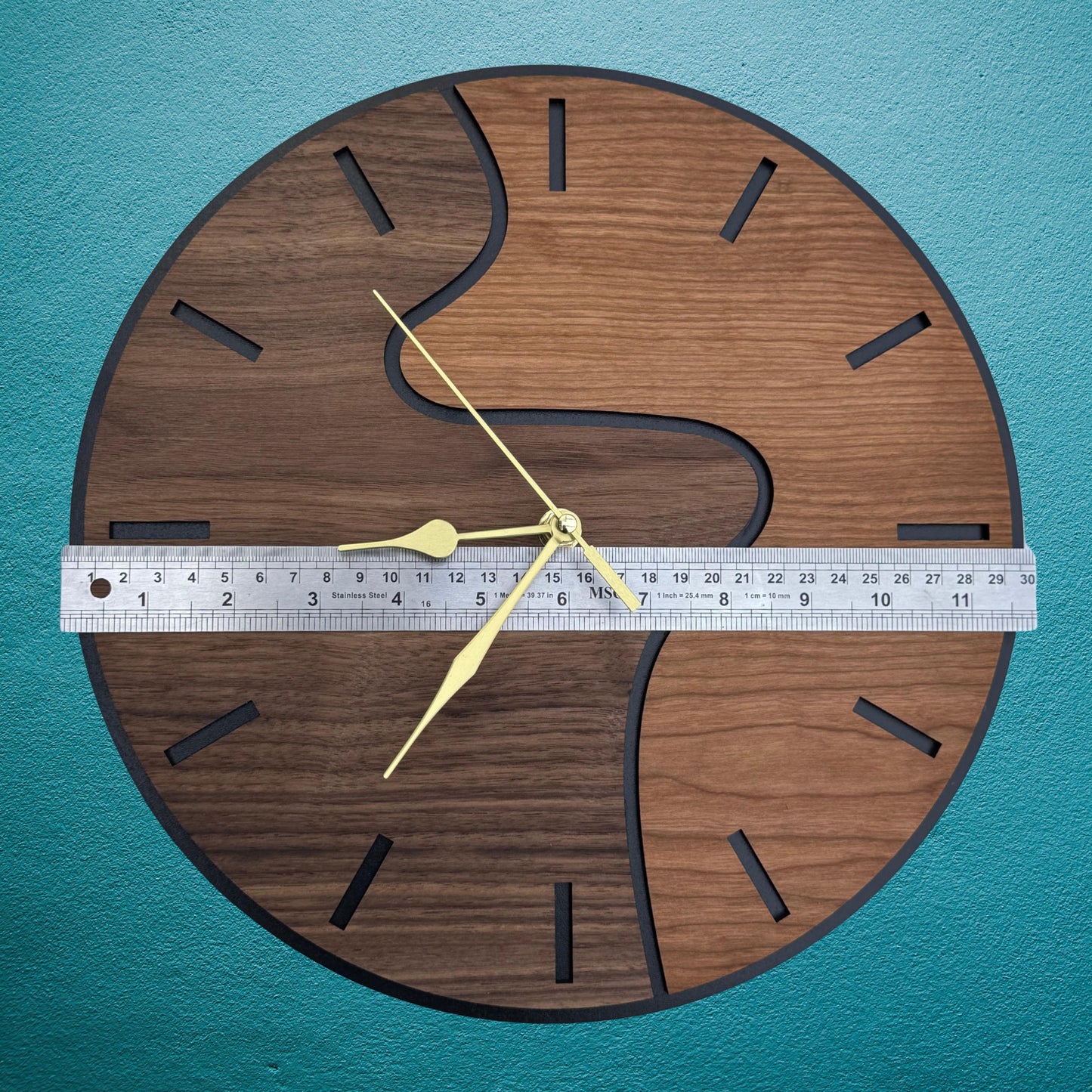 Wooden wall clock with a ruler for scale on a teal background