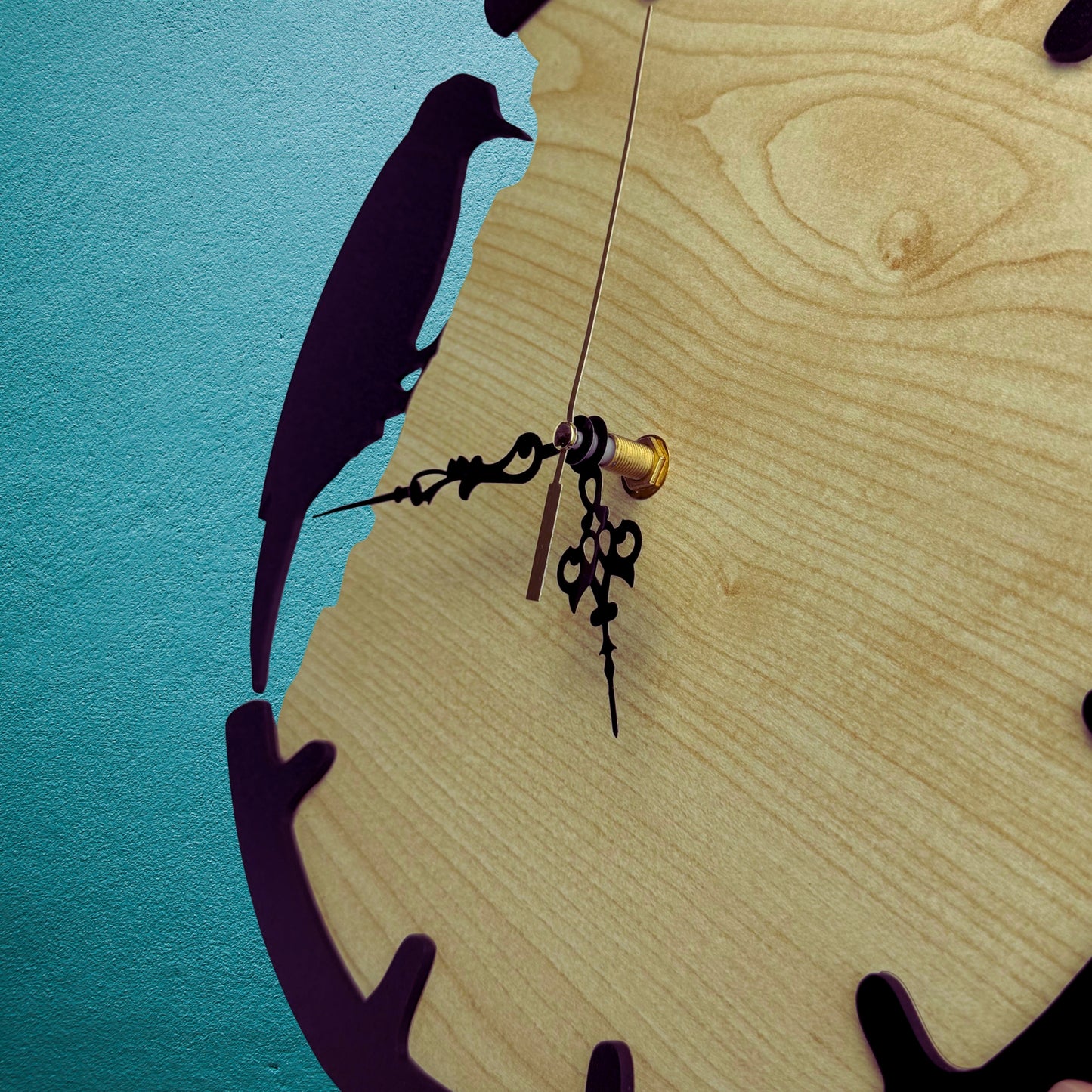 Wooden clock with bird silhouette and decorative hands against a blue background