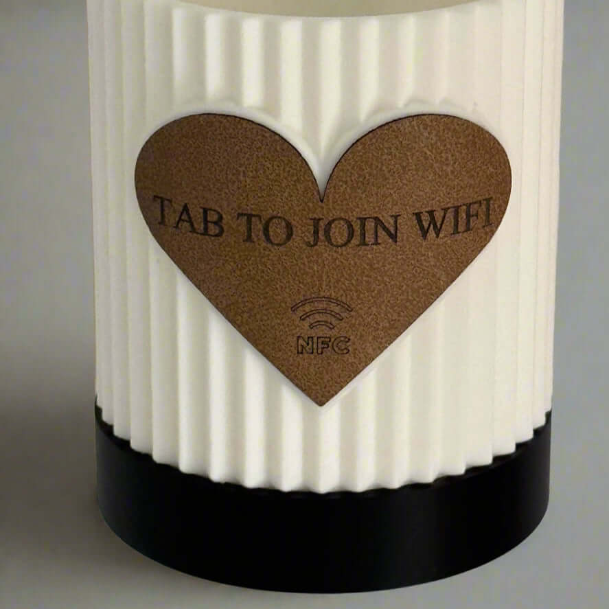White textured candle with a brown heart-shaped label on a gray background