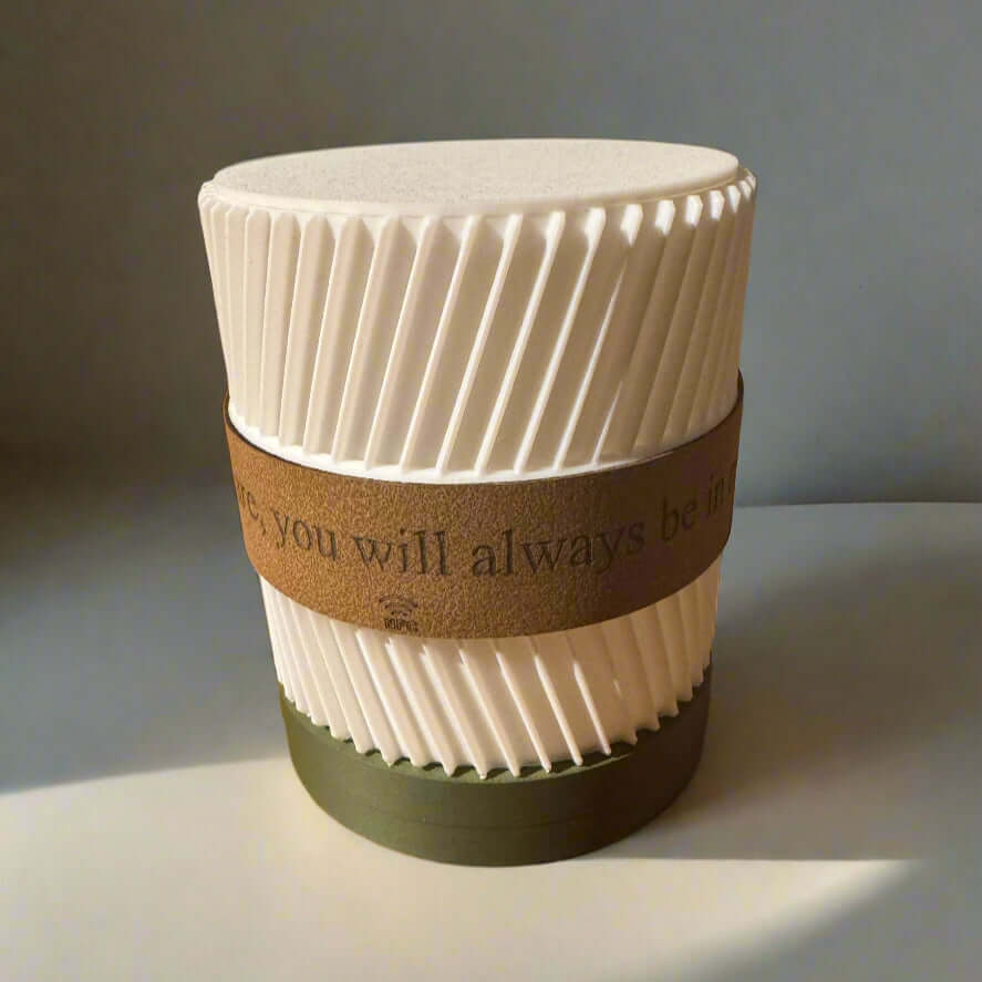 White textured candle with a brown band and text on a gray background