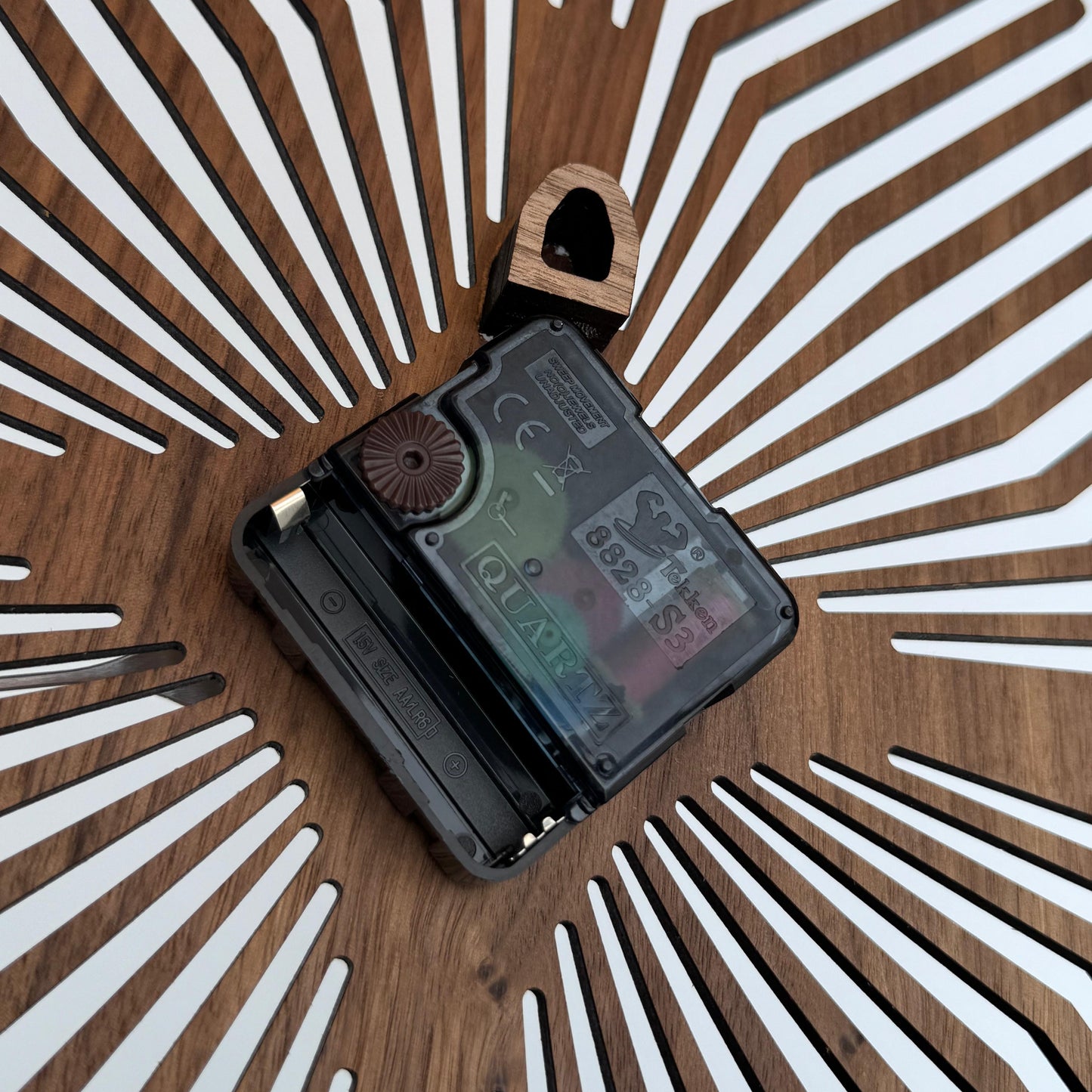 Small electronic device on a wooden surface with a sunburst pattern