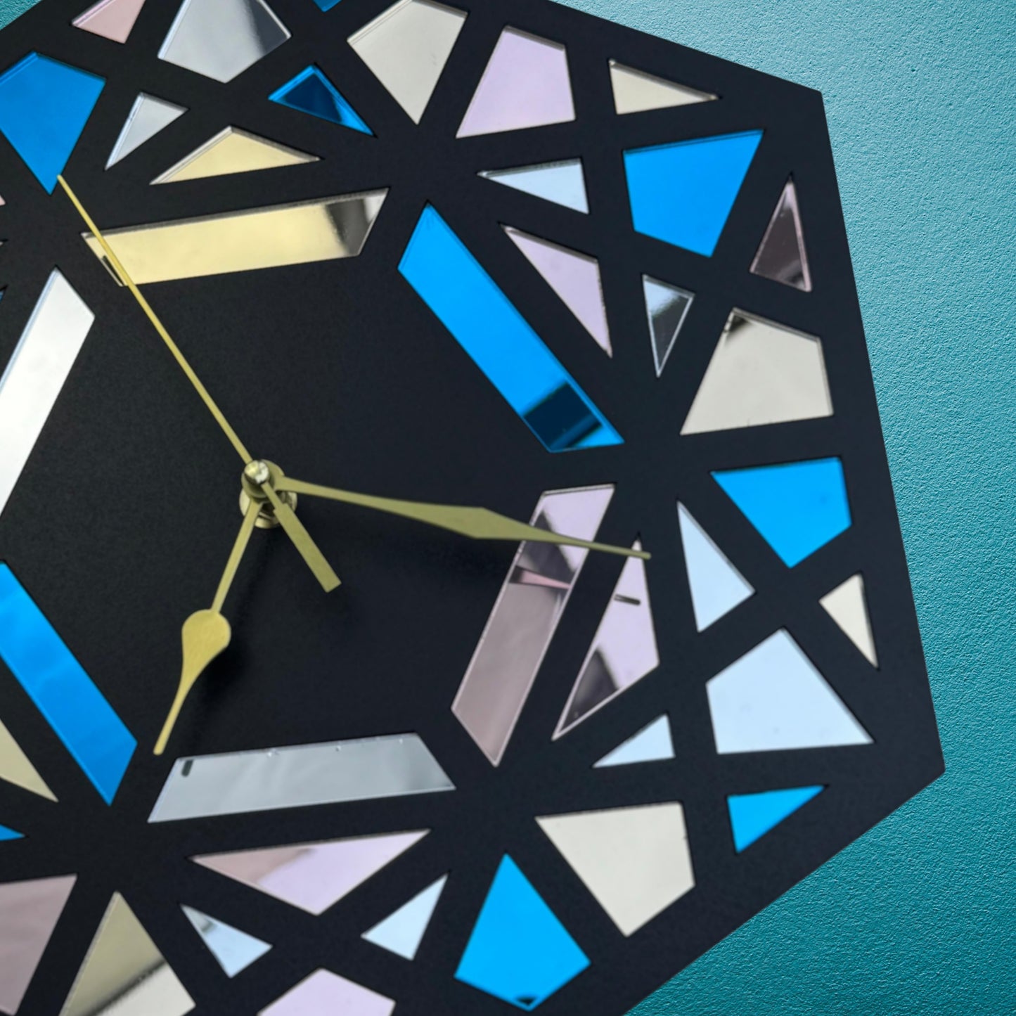 Geometric wall clock with blue and black design on a teal background