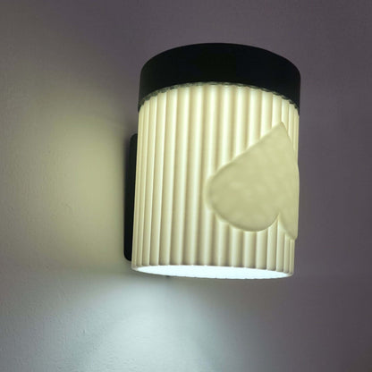 Wall-mounted light fixture with ribbed design and heart shape on a gray background