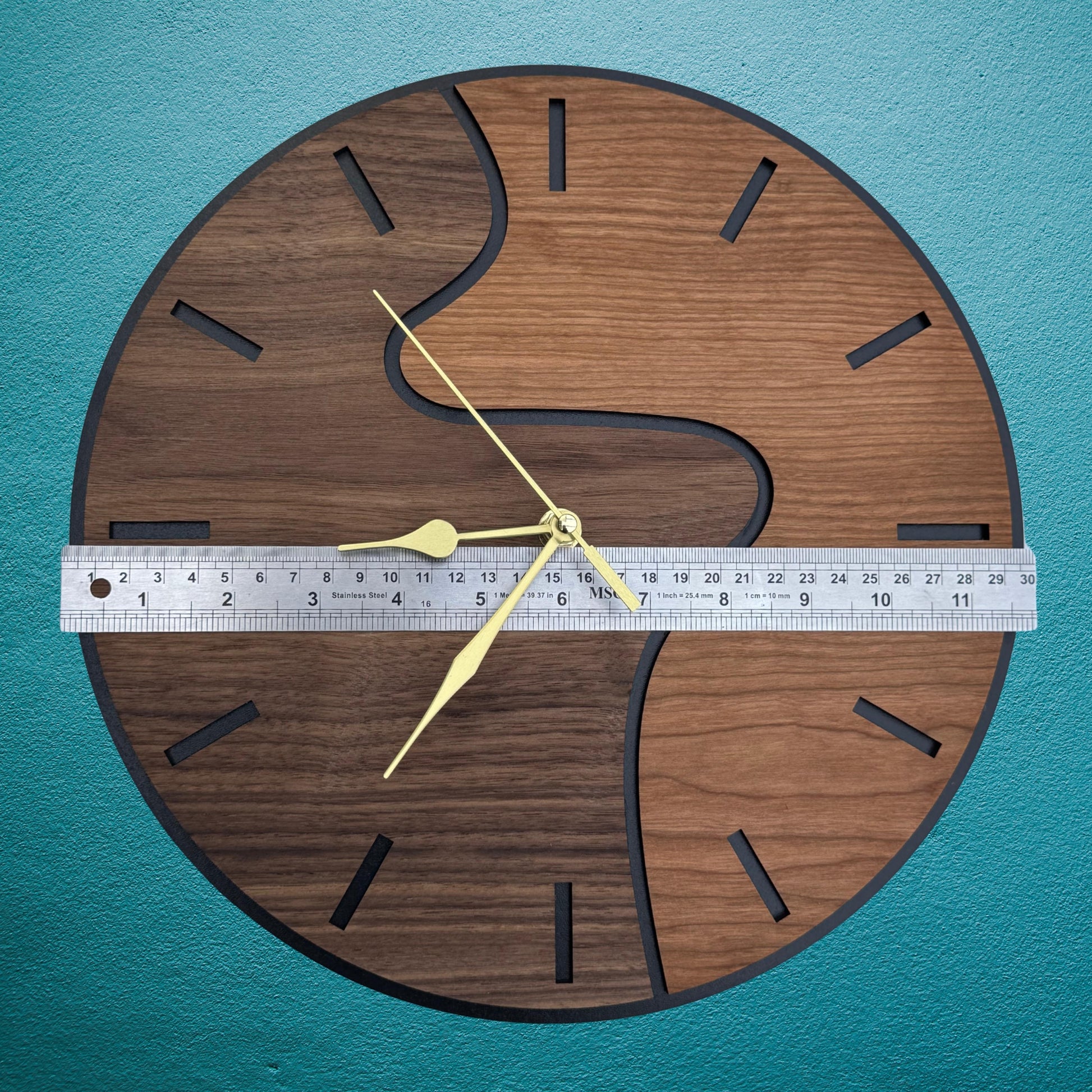 Wooden wall clock with a ruler for scale on a teal background