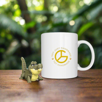 White mug with a logo and text on a wooden surface with toy alligator