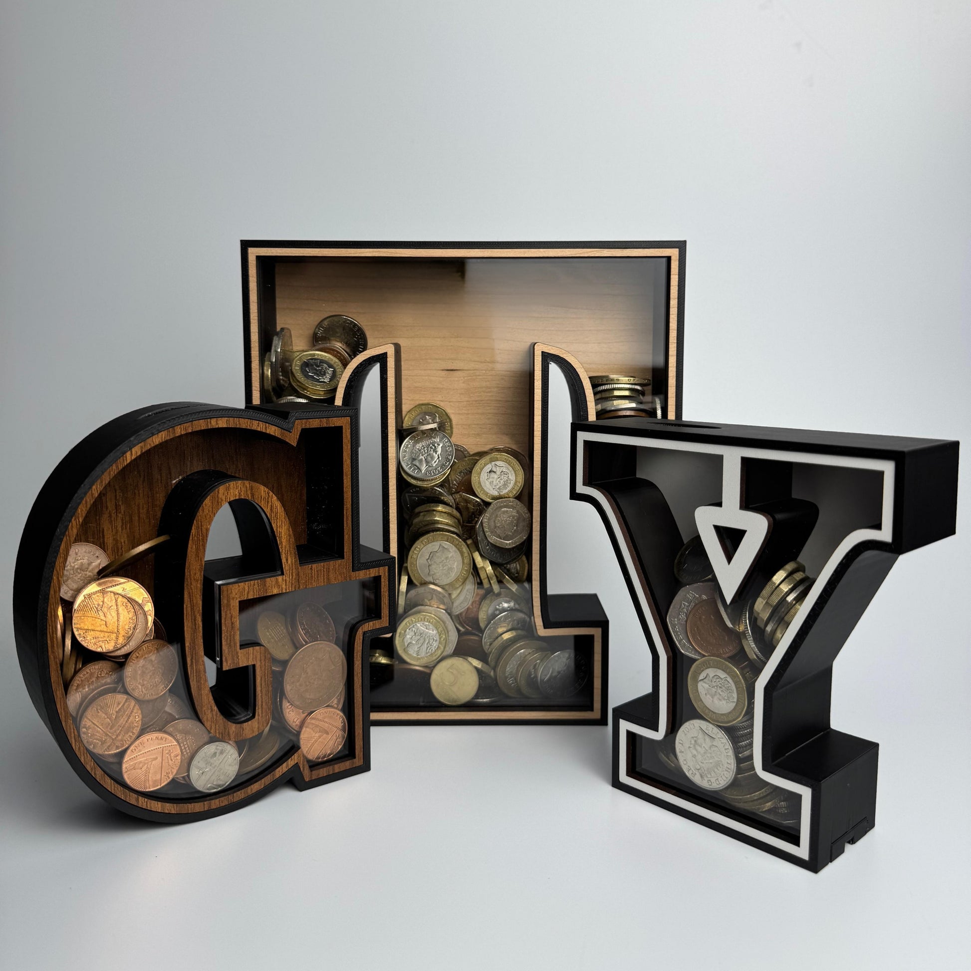 Decorative letter-shaped coin banks with coins inside on a white background