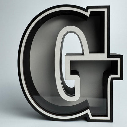 3D letter 'G' with a metallic finish on a light gray background