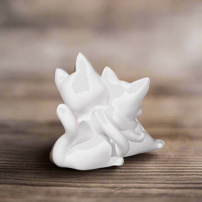 Hugging cat figurine placed on a wooden surface, with soft lighting highlighting the gentle curves and emotional warmth of the piece.

