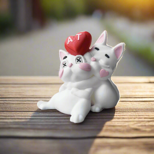 Close-up of two 3D-printed hugging cats with a red heart on one of their heads, symbolizing love, affection, and togetherness in a sweet minimalist design.