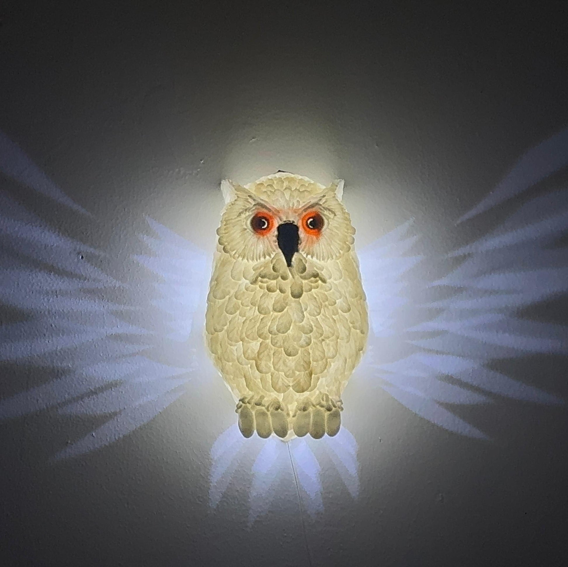 Side view of the Hedwig the Owl Night Lamp mounted on the wall, with light gently spreading from the owl's wings