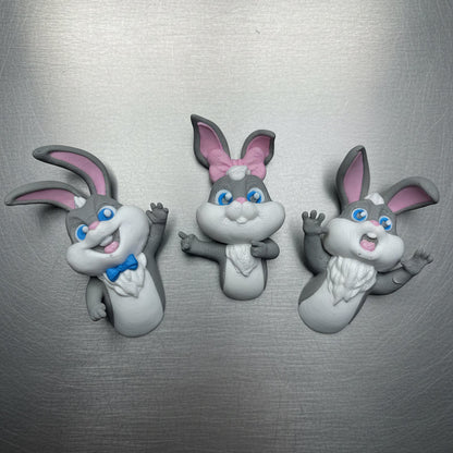 Three cartoon rabbit figurines on a metallic surface