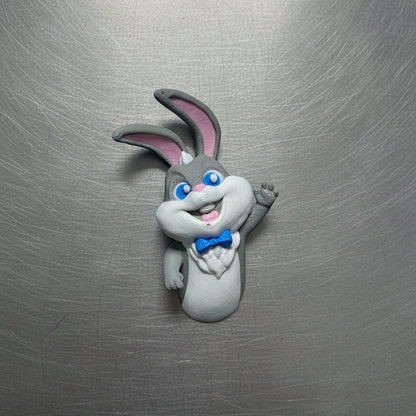 Fridge magnet shaped like a cartoon rabbit with a blue bow tie on a metallic surface