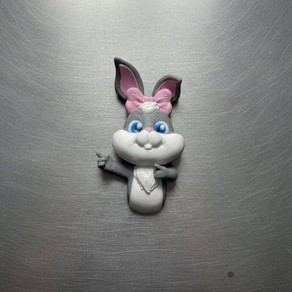 Fridge magnet shaped like a cartoon rabbit with a pink bow on a metallic surface