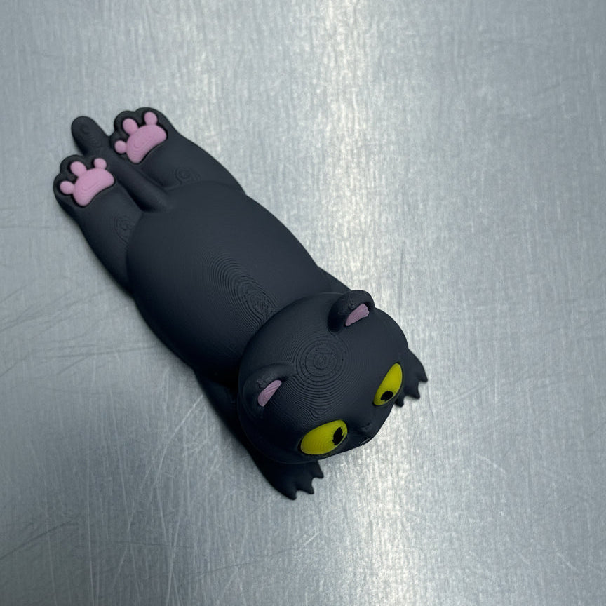 Black cat-shaped phone case with pink paws on a metallic surface