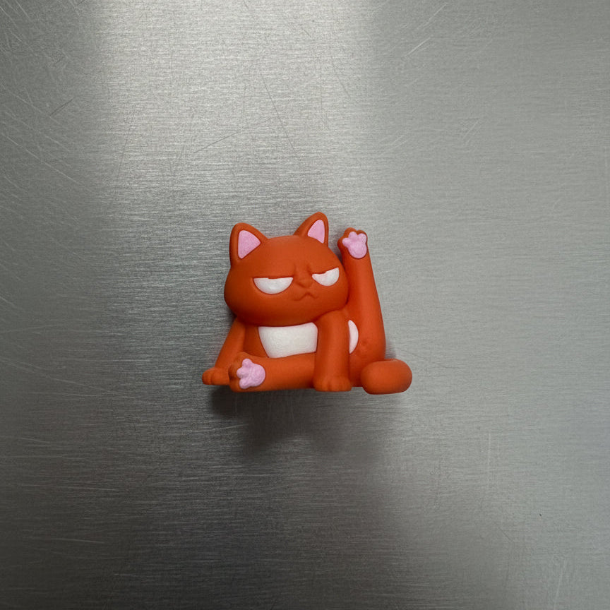 Orange cat-shaped magnet on a metallic surface