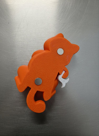 Orange monkey-shaped object with white buttons on a light blue background