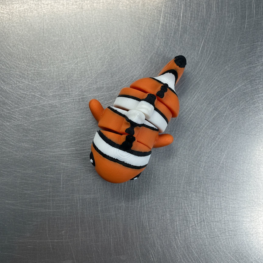 Clay model of a character with orange, black, and white colors on a metallic surface