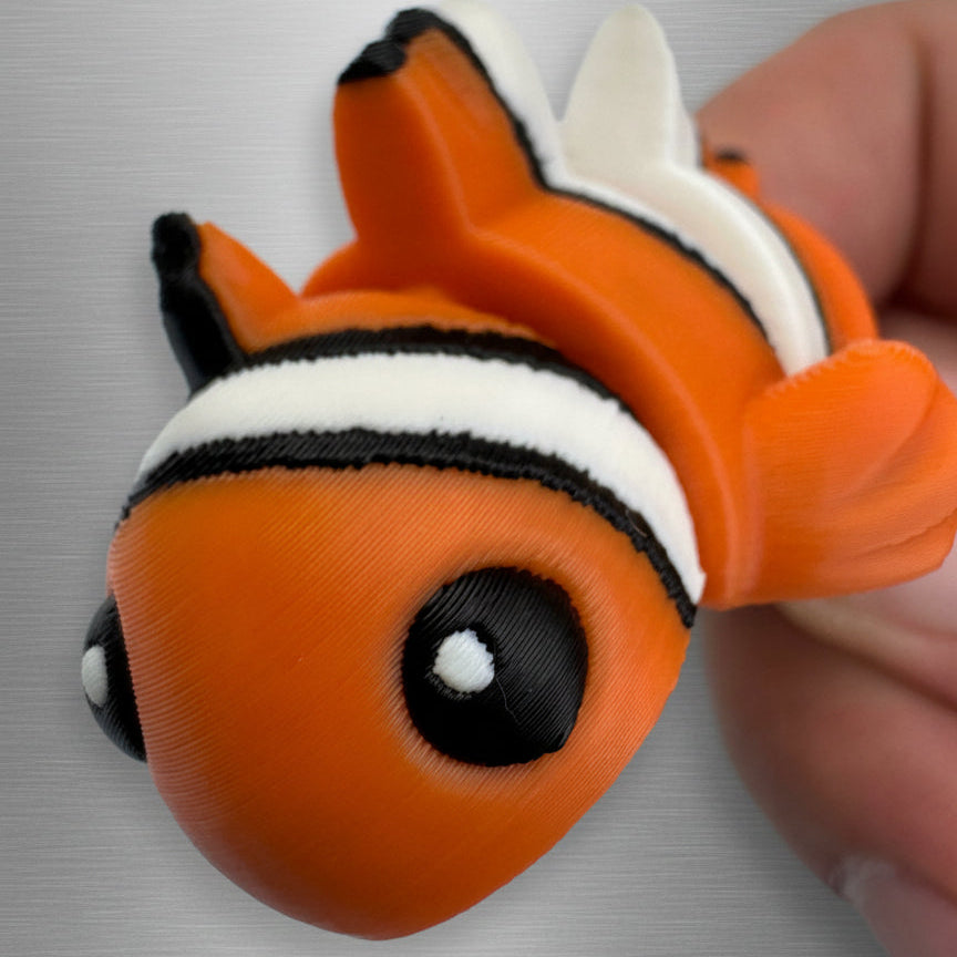 Close-up of a small orange fish toy with a white stripe on a gray background