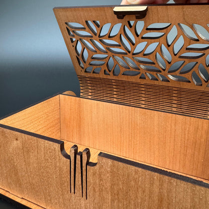 Wooden box with laser-cut leaf design on a gray background