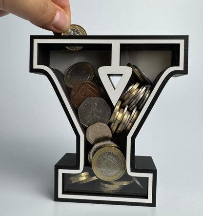 Hand placing coins into a black letter 'Y' shaped container on a light gray background