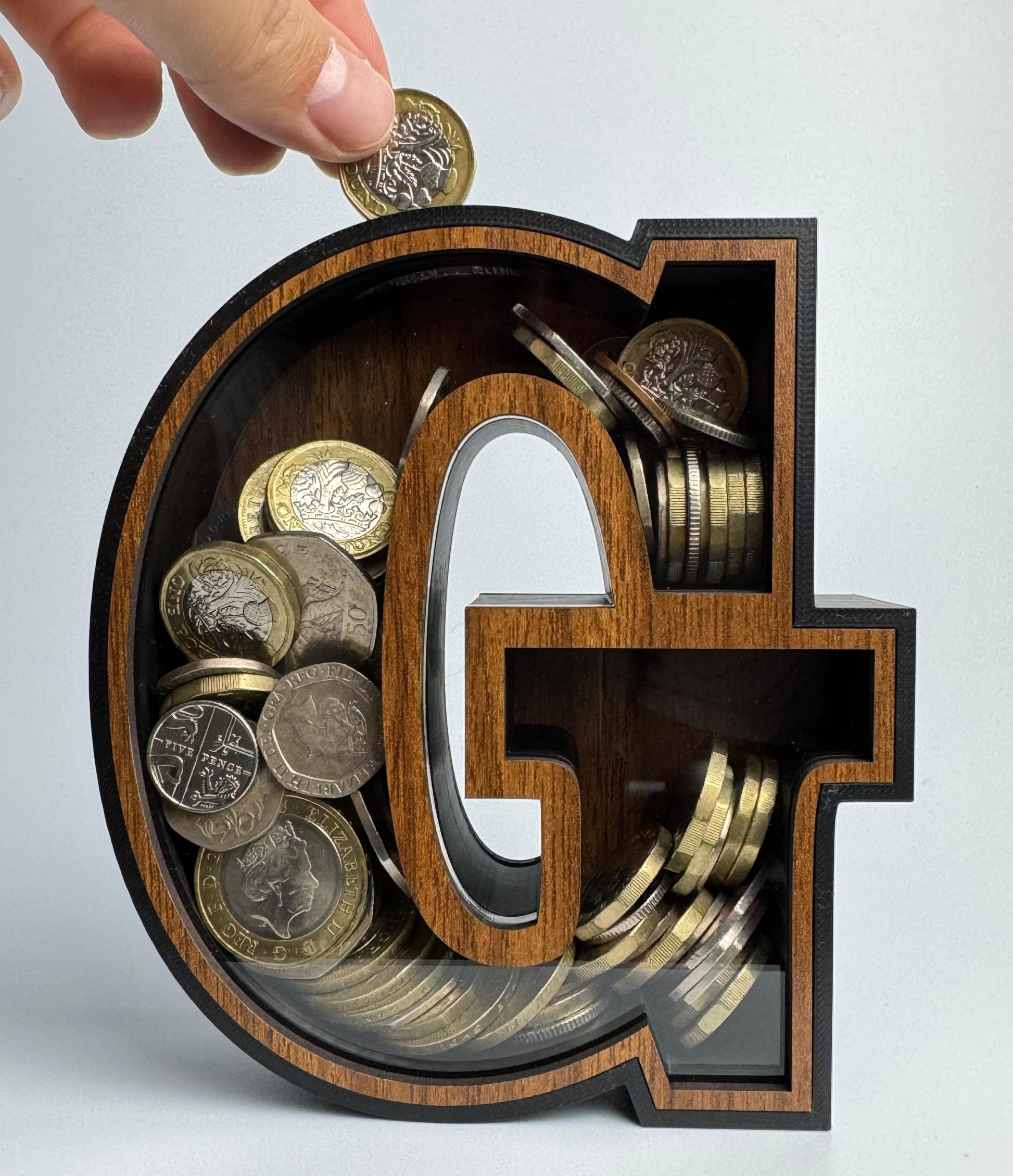 Wooden letter 'G' filled with coins on a light gray background