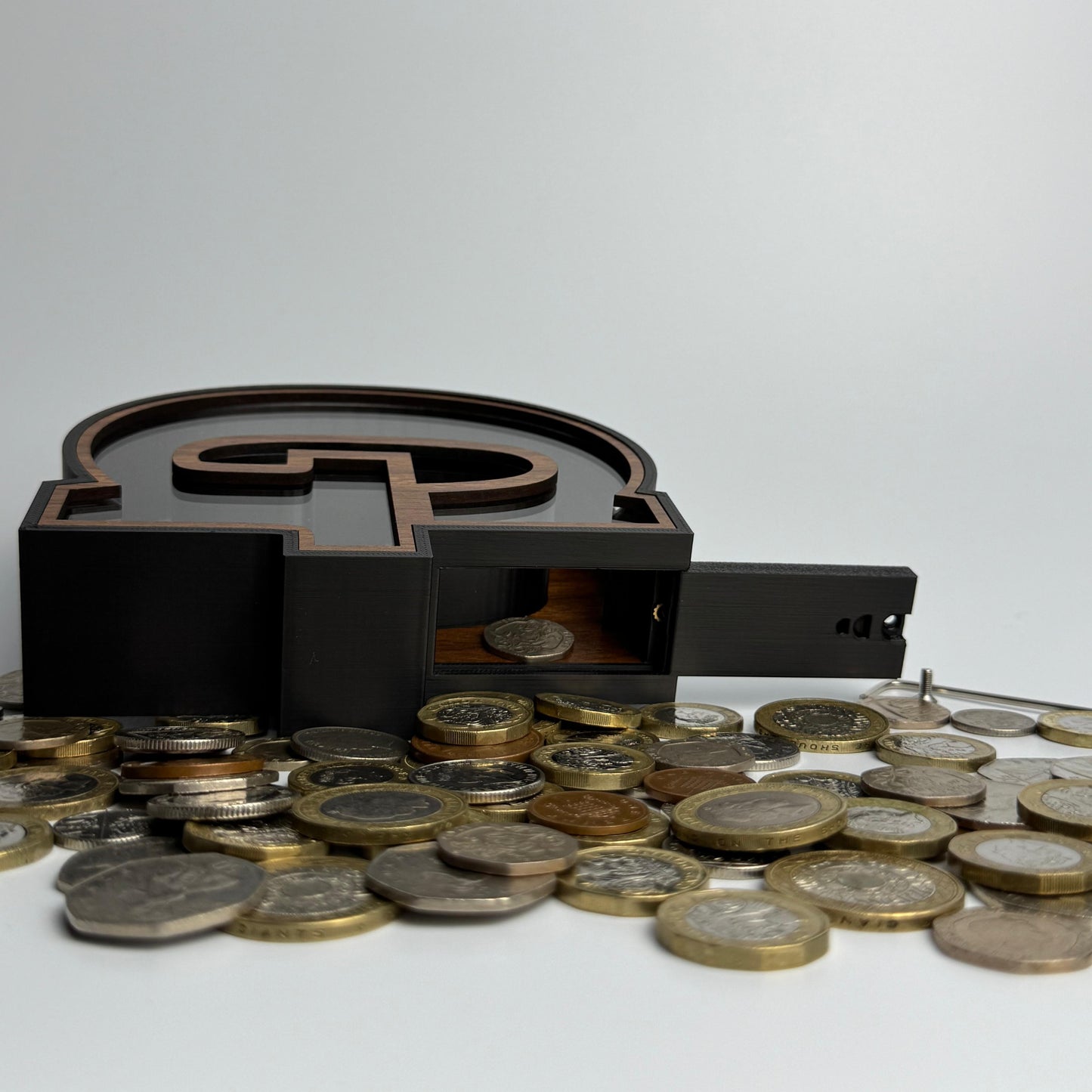 Black money box with coins on a white background
