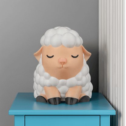Sheep-shaped night light on a blue surface against a gray wall