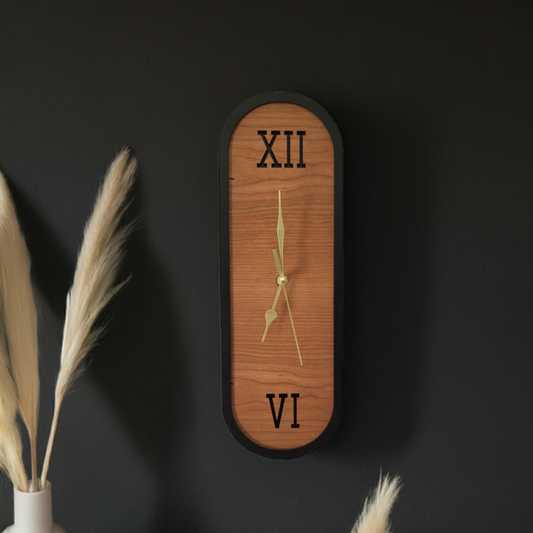 A stunning oval and elongated cherry wood wall clock, showcasing its minimalist face with bold numerals and smooth wooden texture.