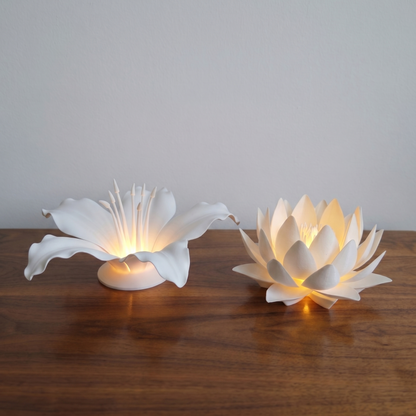 Two white flower-shaped lamps on a wooden surface with a plain background