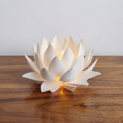 White lotus-shaped candle on a wooden surface with a neutral background